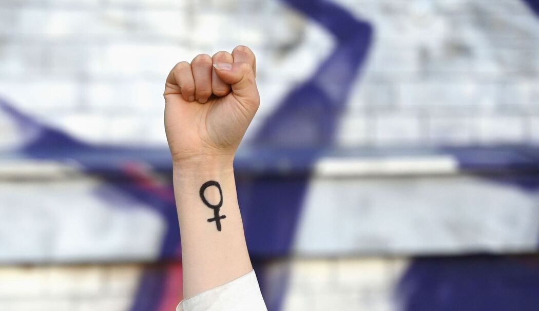 Eine Frau hebt ihre Faust mit Venussymbol die Höhe