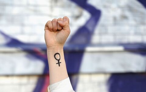 Eine Frau hebt ihre Faust mit Venussymbol die Höhe