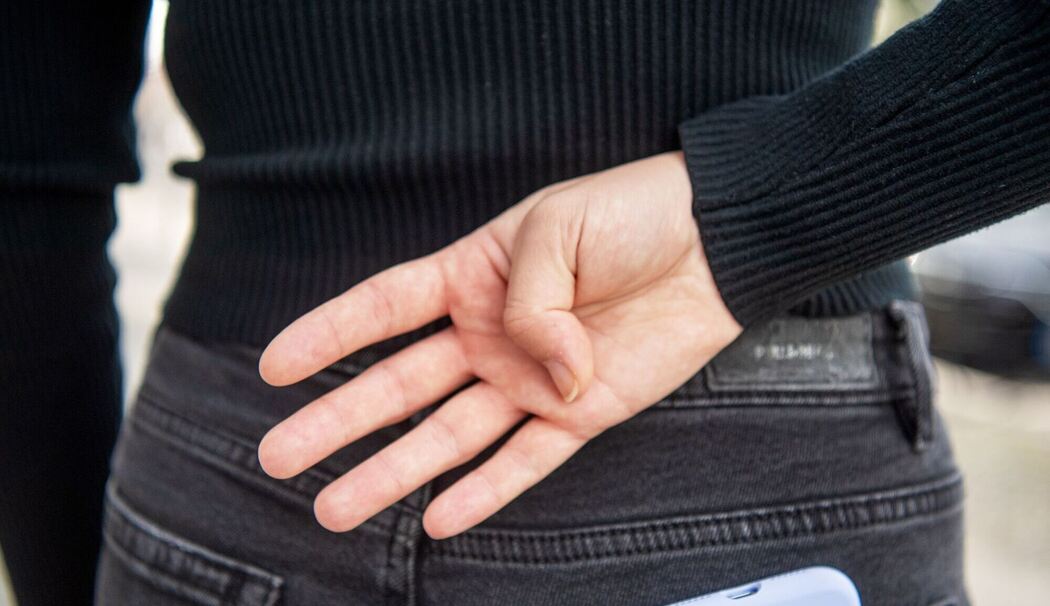 Eine Frau mach ein Handzeichen hinter ihrem Rücken