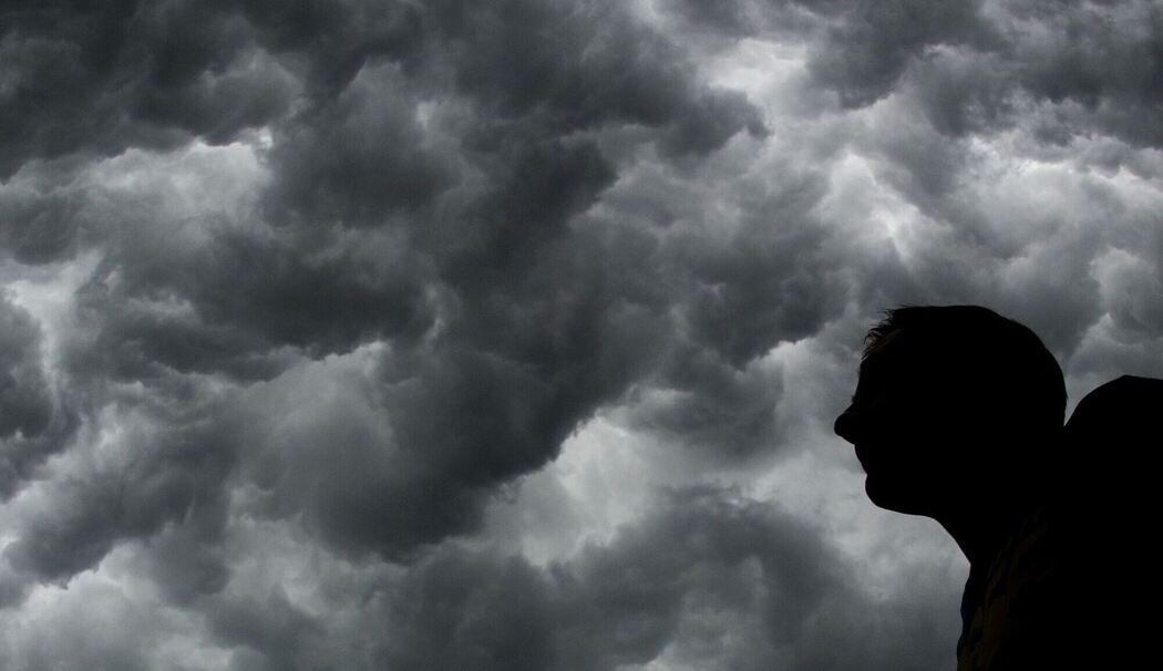 Ein Mann steht unter einem stürmischen Himmel Ein Mann steht unter einem stürmischen Himmel