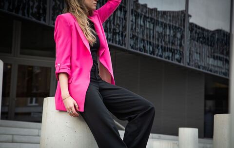 Eine junge Frau trägt einen Neon Pink Blaser