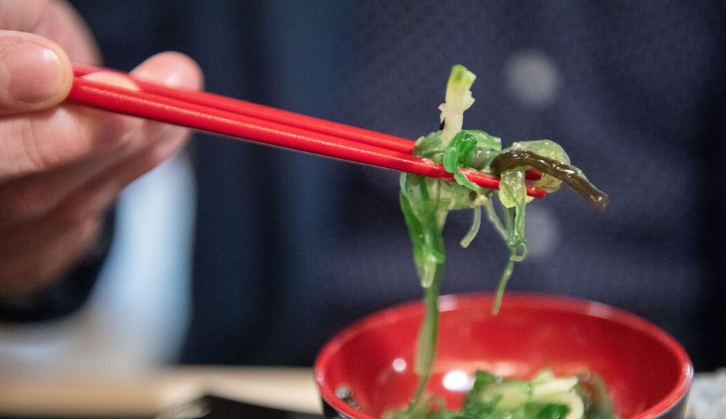 Ein Mann isst einen Wakame-Algensalat Ein Mann isst einen Wakame-Algensalat