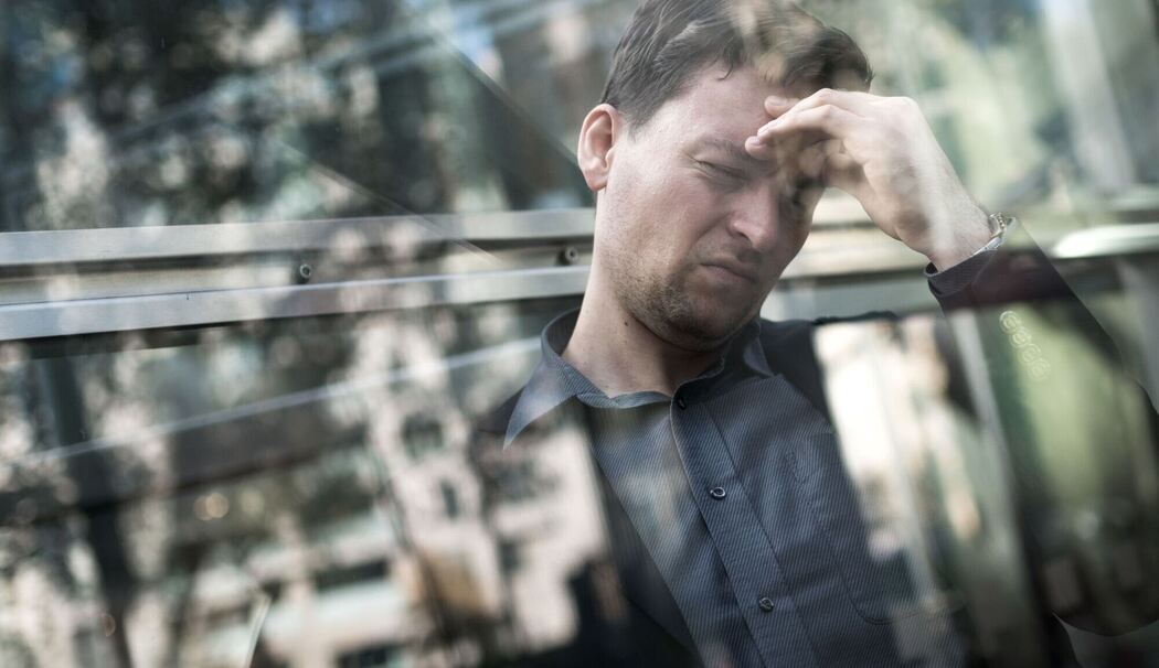 Gestresster Mann greift sich an die Stirn Gestresster Mann greift sich an die Stirn