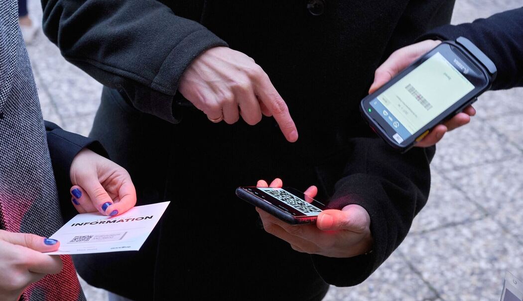 Ein Mann zeigt auf einen QR-Code den eine Frau Scannt