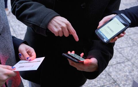 Ein Mann zeigt auf einen QR-Code den eine Frau Scannt