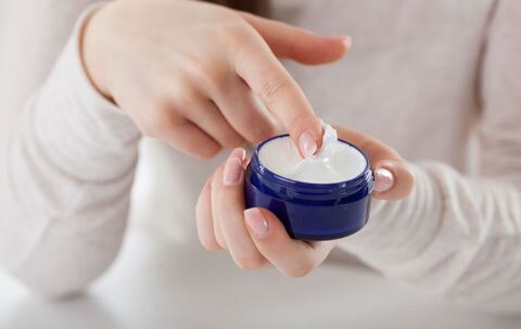 Eine Frau streicht mit dem Finger durch eine Cremedose