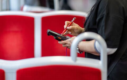 Eine Fahrkartenkontrolleurin kontrolliert einen Fahrgast