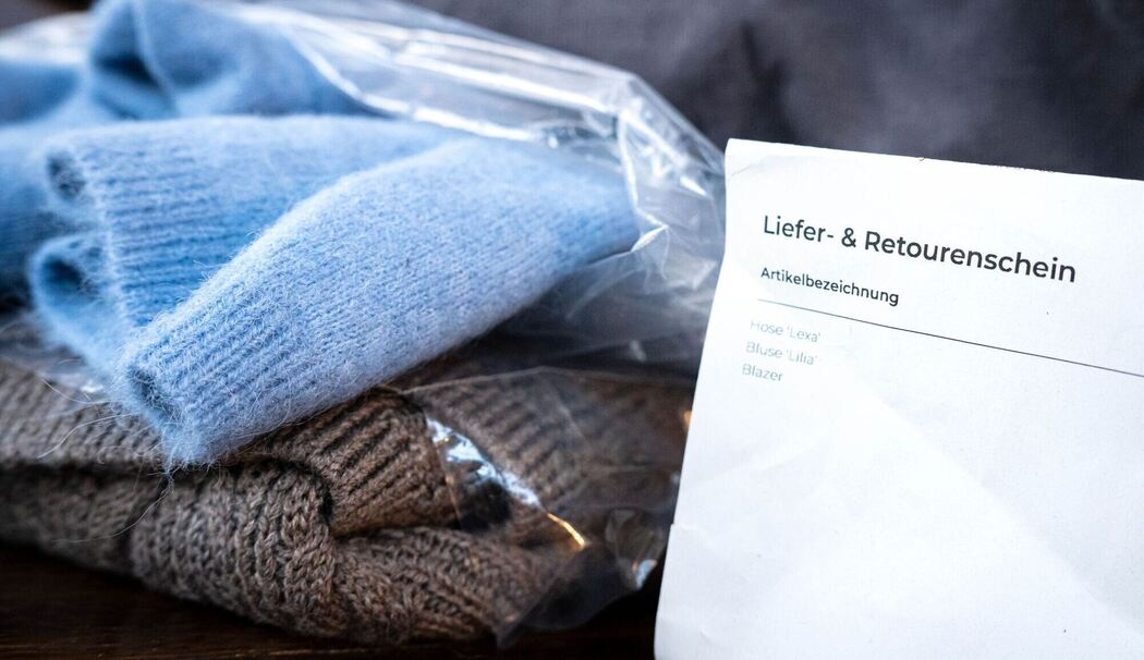 Liefer- und Retourenschein liegt neben online bestellter Kleidung