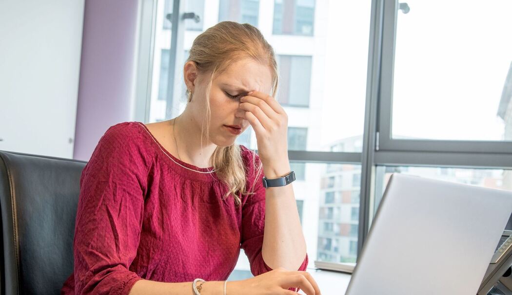 Eine Frau reibt sich die Augen am Arbeitsplatz