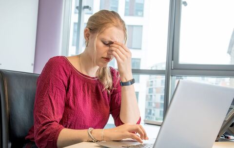Eine Frau reibt sich die Augen am Arbeitsplatz