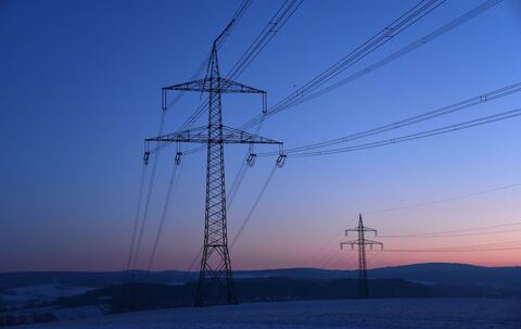 Strommasten in der Morgendämmerung auf einem Feld
