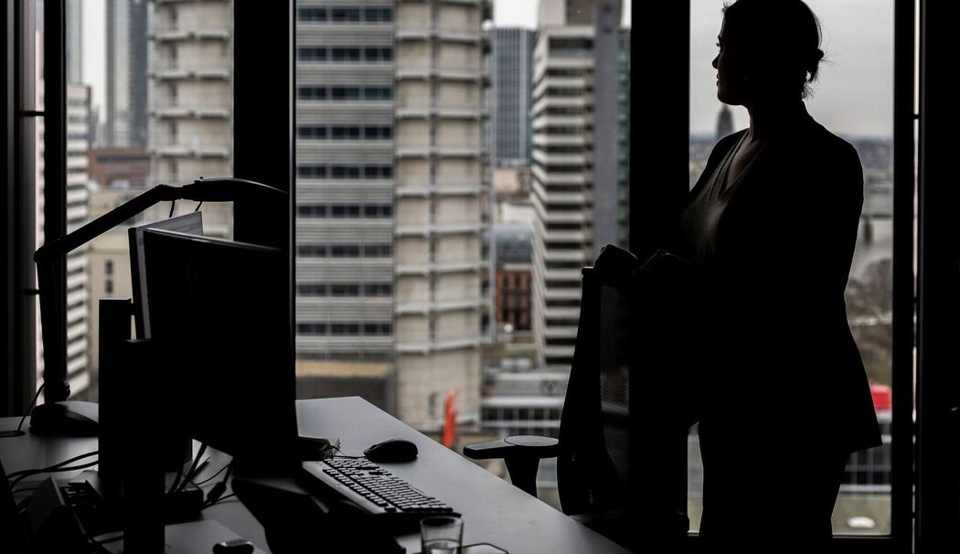 Frau steht an ihrem Arbeitsplatz am Fenster