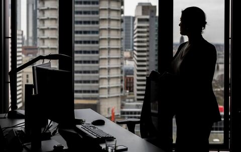 Frau steht an ihrem Arbeitsplatz am Fenster