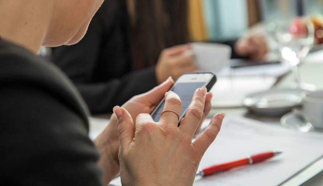 Eine Frau mit Smartphone am Arbeitsplatz