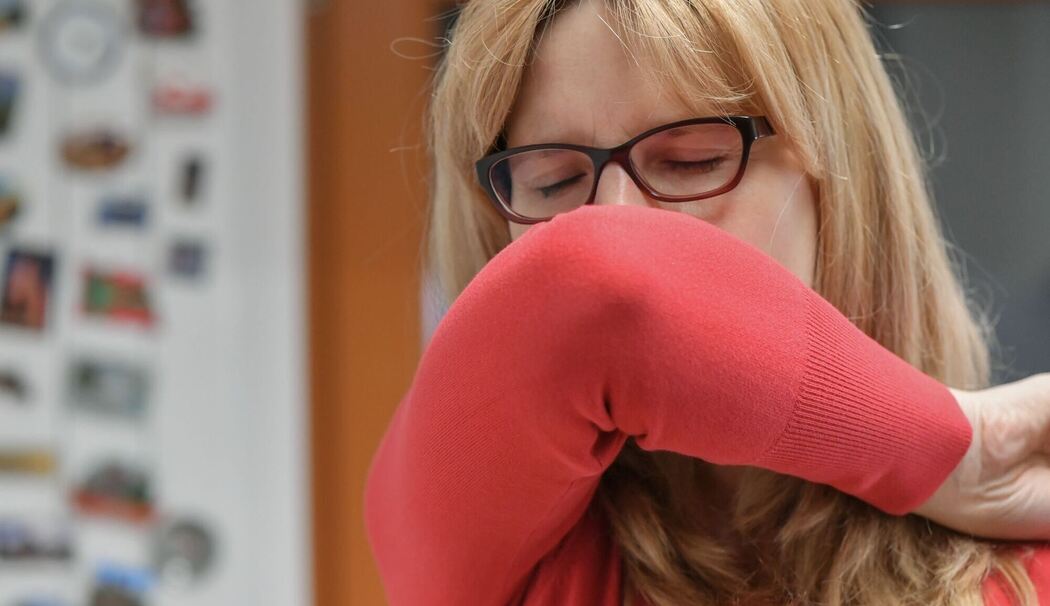 Eine Frau hustet in ihre Armbeuge