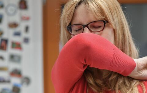 Eine Frau hustet in ihre Armbeuge 