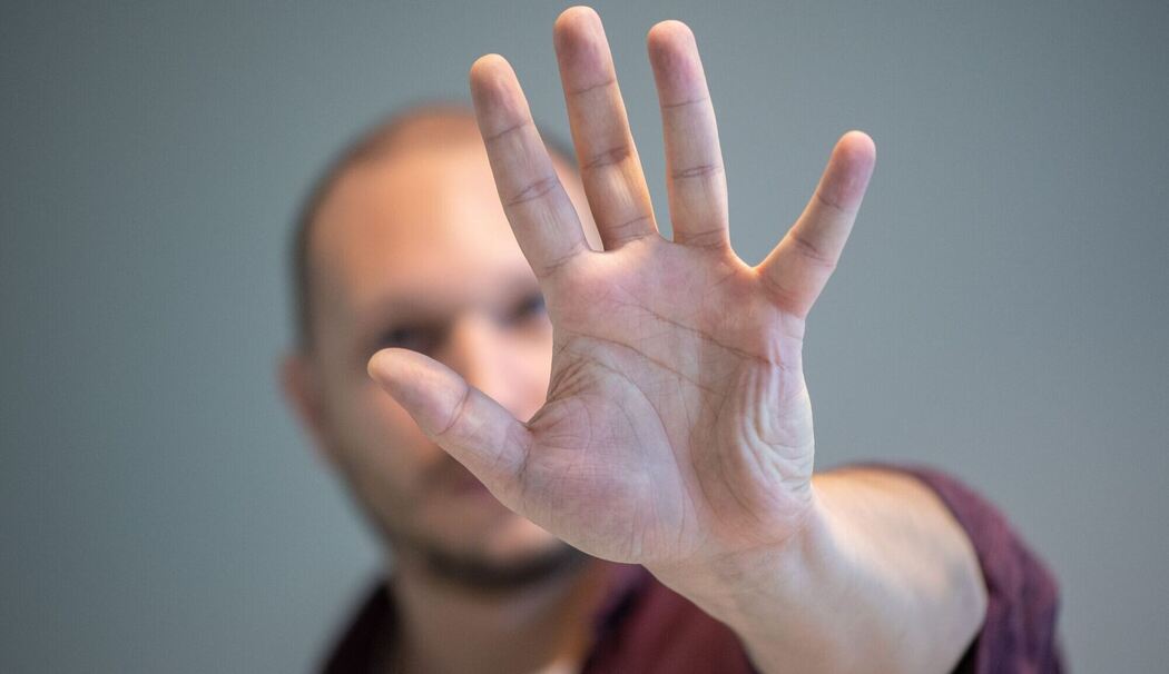 Ein Mann hebt schützend die Hand vor sein Gesicht Ein Mann hebt schützend die Hand vor sein Gesicht