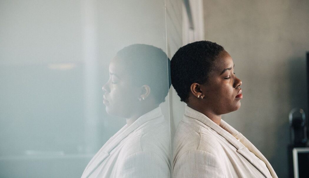 Eine junge Frau lehnt nachdenklich an einer Glaswand