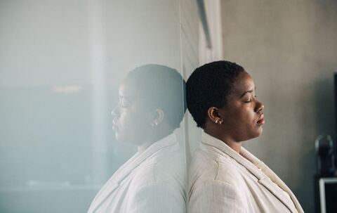 Eine junge Frau lehnt nachdenklich an einer Glaswand